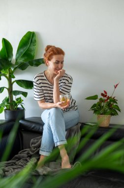 Hayalperest genç kadın, kanepede oturuyor ve sıcak bir fincan çayın tadını çıkarıyor..