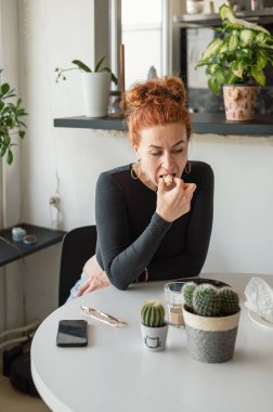 Çekici, olgun bir kadın sıcak mutfağında yemek yiyor. Günlük hayatın huzurlu anı..