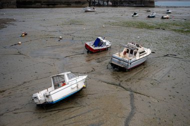 Dalgalar çekildiğinde Granville limanının manzarası. Kum ve liman duvarları üzerinde dinlenen tekneler..