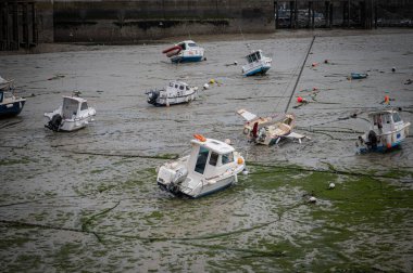 Dalgalar çekildiğinde Granville limanının manzarası. Kum ve liman duvarları üzerinde dinlenen tekneler..