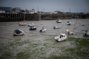 Dalgalar çekildiğinde Granville limanının manzarası. Kum ve liman duvarları üzerinde dinlenen tekneler..