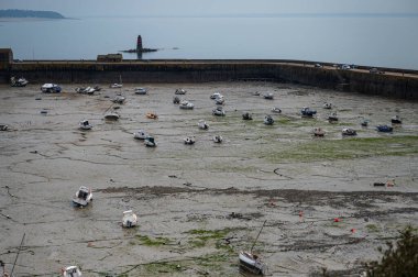 Granville, Fransa - 12 Nisan 2025: Dalgalar çekildiğinde Granville limanının manzarası, kumların ve liman duvarlarının üzerinde dinlenen tekneler.