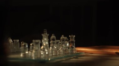 Akşamleyin pencere ışığında bir masada günlükle cam satranç oyunu