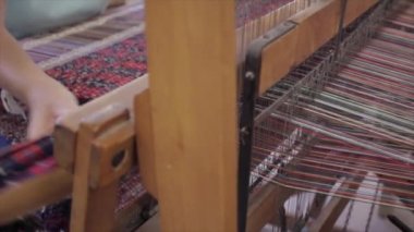 Zanaatkar dokuma tezgahında renkli bir halı dokuyor.