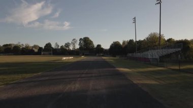 Sporcular alacakaranlıkta lise pistinde koşup antrenman yapıyorlar..