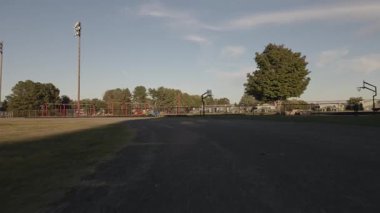 Geniş bir parkta sakin bir gün. Ağaçlar ve oyun parkları yumuşak gün ışığında..