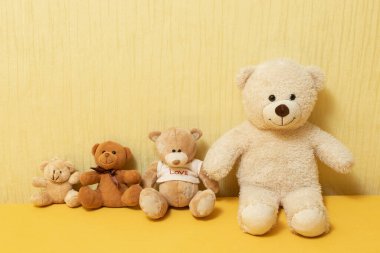 Four teddy bears sit on the bed, yellow background