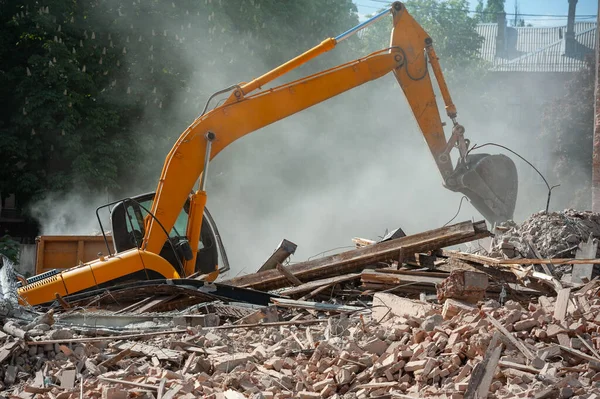 stock image Demolition of building. Excavator breaks old house. Freeing up space for construction of new building.