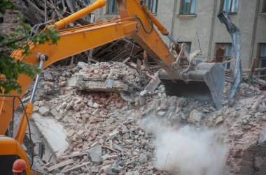 Binanın yıkımı. Kazıcı eski evi yıkıyor. Yeni bina inşaatı için yer açılıyor.