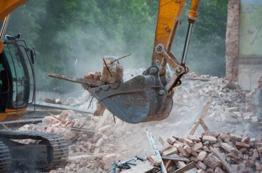 Demolition of building. Excavator breaks old house. Freeing up space for construction of new building. clipart