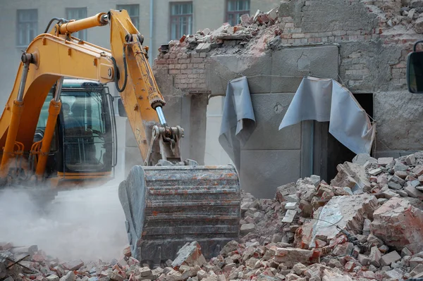 Demolition of building. Excavator breaks old house. Freeing up space for construction of new building.