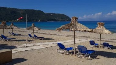 Güneş yataklı, doğal şemsiyeli, ufuk ve derin mavi deniz manzaralı ıssız bir sahil..