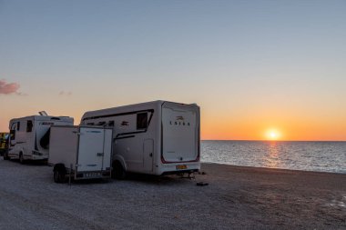 Lefkada adası. Yunanistan-10.17.2022. Kathisma Sahili 'nde güzel bir gün batımı manzaralı bir kamp arabası..