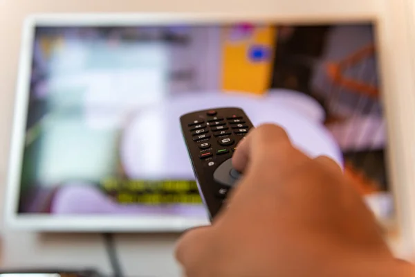 Televizyonun uzaktan kumandasını kullanan biri..