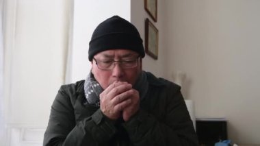 Ev enerjisi iki kattan fazlaya mal olduğu için evin içinde sıcak kalmaya çalışan kıdemli bir adam..
