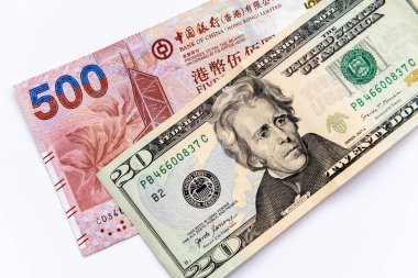 Beyaz arka planda yirmilik bir Amerikan Doları ve beş yüz Hong Kong Doları banknot var..