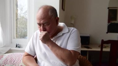 A elderly man coughing. Suffering the symptoms of Winter cold and flu.