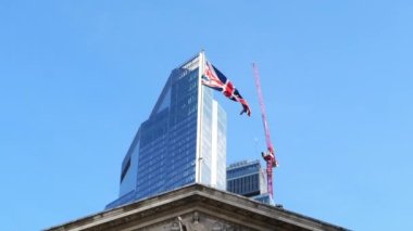 London. UK-02.19.2023. Historic and modern buildings in the City of London with the Union Jack flying in the wind. The Royal Exchange and Twenty Two 