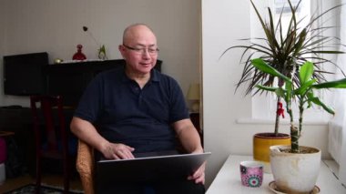 Elderly man relaxing at home using a laptop computer.
