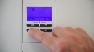 Enerji enflasyonundaki yükselen artışla başa çıkmak için ısıtıcının ısısını düşüren bir kişi.