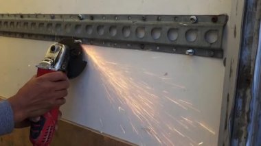 Metal cıvata kesmek için açı öğütücü kullanan biri..