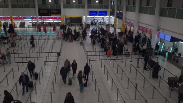 Gatwick 2023ガトウィック空港南ターミナルのホールでは 多くの乗客が彼らのフライトをチェックインしています — ストック動画