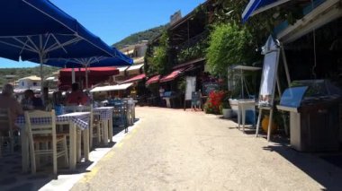 Lefkada adası. Yunanistan - 06.18.2023. Sivota 'da turist kıyı şeridi boyunca bir yürüyüş. Tatil turistleri için restoran ve mağazalarla dolu bir köy..