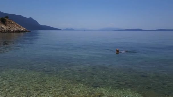 ミティカスだ ギリシャ 2023年 透き通った海で泳いでいる女の観光客が海を独り占め — ストック動画