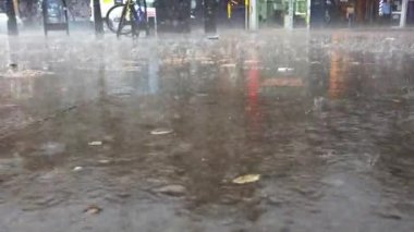 Londra 'ya sağanak yağmur yağıyor. Kaldırımdan büyük yağmur damlaları yükseliyor..