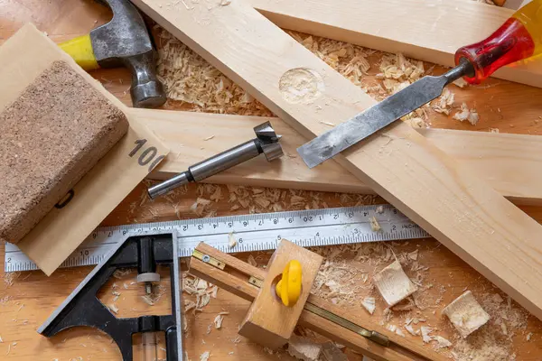 Timber, wood shavings and carpentry tools on a work bench.