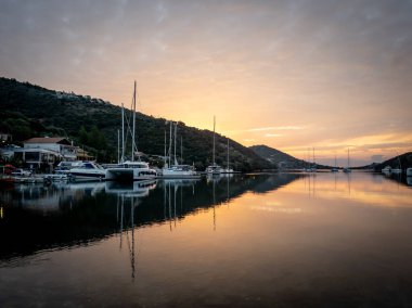 Gün doğumu bulutları durgun deniz limanında yansıyor. Sivota. Lefkada. Yunanistan.