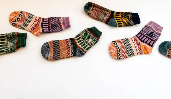 Colourful woollen Winter socks arranged in a staggered row isolated in white.