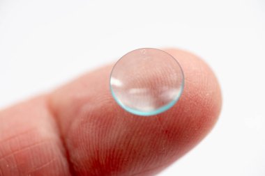 Göz teması lensinin ön görüntüsünü kapat. Beyazla izole edilmiş parmağın üstünde..