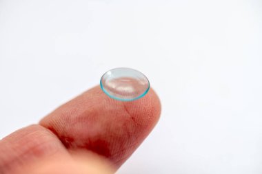 Üzerinde göz kontaktı lensi olan bir parmak beyaz bir arkaplanda izole edilmiş.