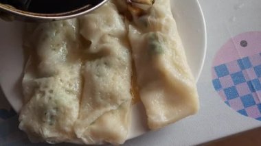 Sosu bir tabak buharda pişmiş karides rulosunun üzerine dökerek, har cheung.