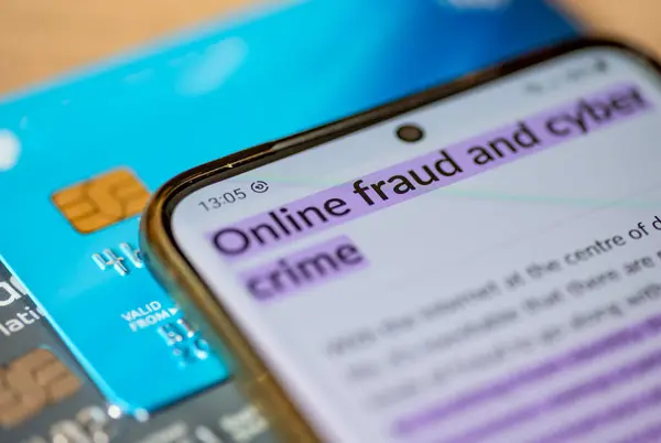 An online fraud and cyber crime concept, with a smart phone which has the words online fraud and cyber crime, on top of bank cards.