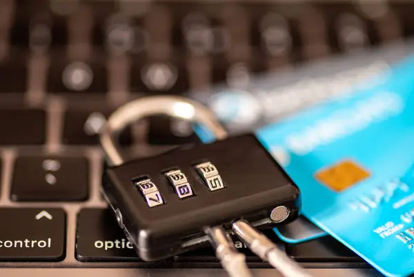 An online payment security concept with a combination padlock and credit, debit bank cards on the keyboard of a laptop computer.