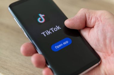 Londra mı? UK- 04.18.2024. Sosyal medya uygulaması Tiktok adı ve logosu ekranda olan bir cep telefonunu tutan bir el.