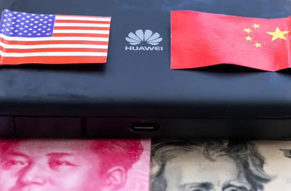 Stock image London. UK- 04.26.2024. A technology political economic concept. The a logo on a Huawei device in the middle of the Chinese and US national flag and bank notes underneath.