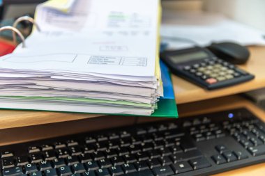 Close up of a business work station with a folder of invoices, calculator, computer keyboard and mouse. Business accounting concept.
