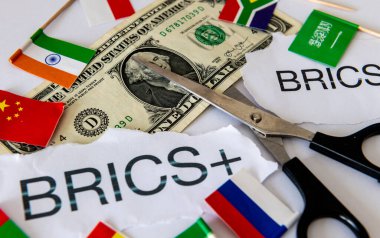 A dedollarisation concept with the words and country flags of the block of BRICS and BRICS+ countries, a pair of scissors and a US dollar bill. clipart