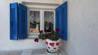 Geleneksel bir Yunan köy evinin mimari ayrıntıları. Mavi panjurlu bir pencere, bir masa ve evin içine kurulmuş bir oturma odası..