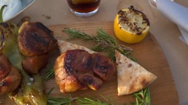 Geleneksel Yunan usulü ızgara domuz eti, ahşap bir tahtada pide ve limonla servis edilir..