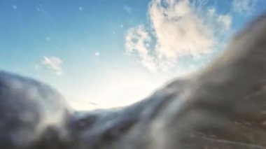 Deniz dalgalarının alçak açılı klipleri güzel gökyüzü bulutlarıyla gün batımında kumlu bir sahile vuruyor..