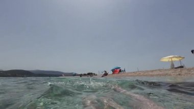 Ammoglossa plajı, Lefkada, Yunanistan-06.26.2024. Denizde yüzen bir yüzücü arkada yüzer ve bacaklarıyla nazikçe tekmeler..