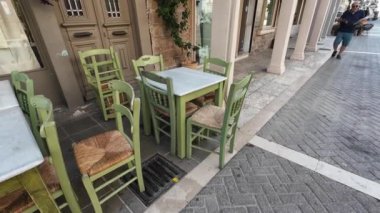 Lefkada Town, Lefkada, Yunanistan-06.30. 2024. Mela caddesinde kapalı bir kafe önünde masa ve sandalyeler.