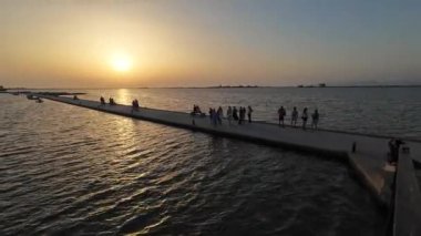 Lefkada Town, Lefkada, Yunanistan-06.30. 2024. Su kanalının ahşap köprüsünden güzel bir manzara ve yerel halk ve turistlerle birlikte büyüleyici günbatımının tadını çıkarıyorlar..
