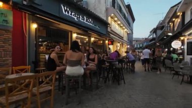 Lefkada Town, Lefkada, Yunanistan-06.30. 2024. Mela Caddesi 'nde akşam yürüyüşü. Yerel ve turist kalabalığı yemek ve alışveriş yapıyor..