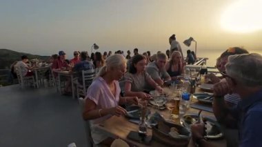 Exanthia, Lefkada, Yunanistan-07.01.2024. Güzel gün batımı manzaralı bir akşam yemeği ve Rachi Restoranı 'nda dostane bir garson servisi..