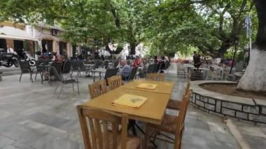 Karya Köyü, Lefkada, Yunanistan-07.02.2024. Köy meydanı, turistlerin, büyük ağaçların gölgesinde ekmek ve içeceklerle uğraştıkları bir yer..